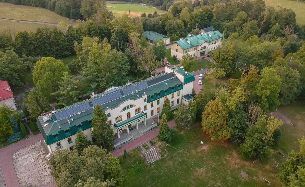 Wykonane dronem zdjęcie Ośrodka "Bucze" przedstawia dwa główne tworzące go budynki, o tej samej kolorystyce - jasne elewacje i zielone dachy. 
