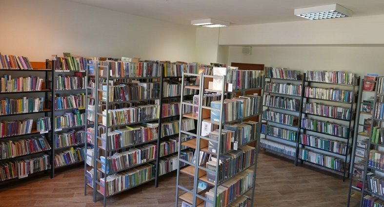 Zdjęcie przedstawia skumulowane obok siebie regały biblioteczne szczelnie wypełnione książkami.