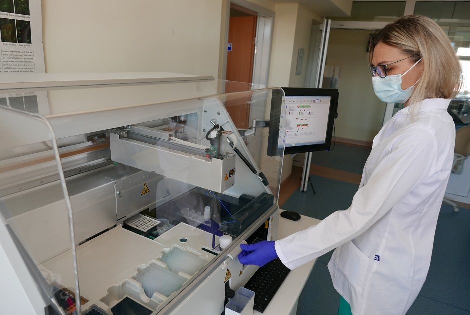 Na zdjęciu fragment jednego z pomieszczeń szpitalnego laboratorium, w którym diagnosta obsługuje urządzenie wykonujące badanie.