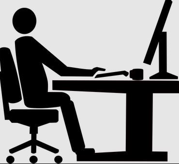 Czarna grafika na szarym tle przedstawia sylwetkę osoby siedzącej przy biurku z komputerem.